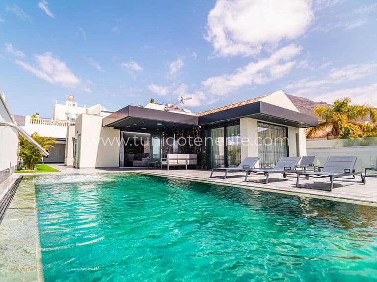 Piscina exterior junto a terraza con tumbonas y pérgola