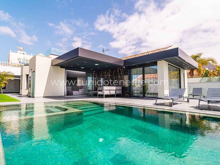 Piscina exterior junto a la terraza y fachada acristalada