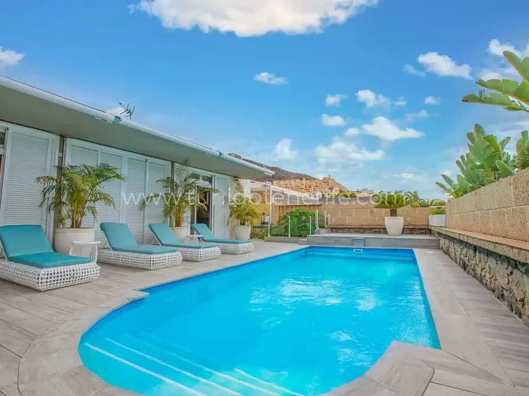 Piscina exterior con tumbonas y cielo despejado