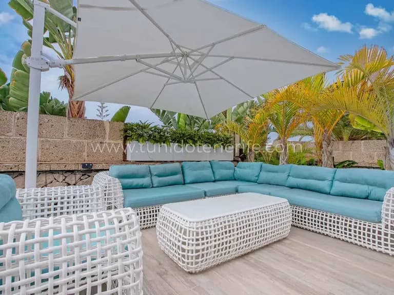 Terraza con sofá en L, mesa baja y gran parasol