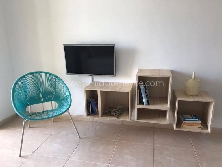 Living cu rafturi modulare, televizor și scaun turcoaz