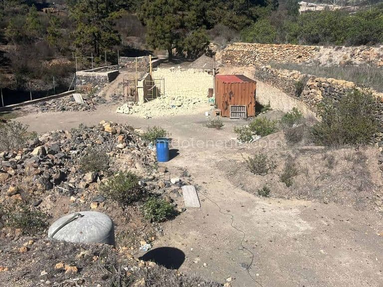 Outdoor lot with rubble, barrels and a small construction shed