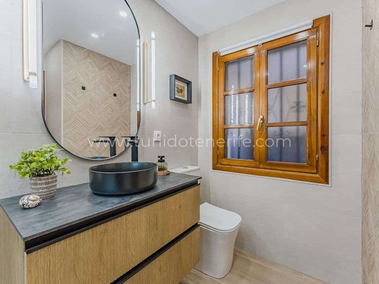 Baie cu chiuvetă neagră, oglindă rotundă și fereastră din lemn