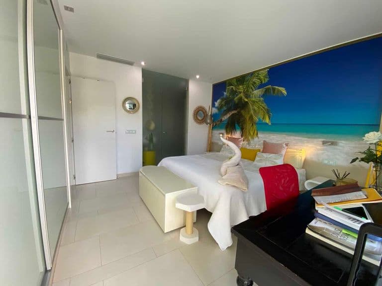 Bright bedroom with white bed, wardrobe and tropical mural