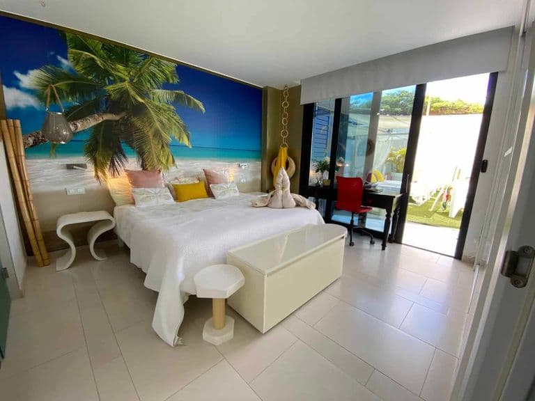Bedroom with tropical mural, white bed and outdoor terrace