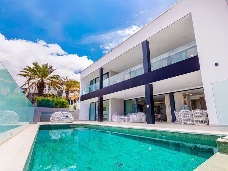 Piscina exterior junto a terraza moderna y fachada blanca