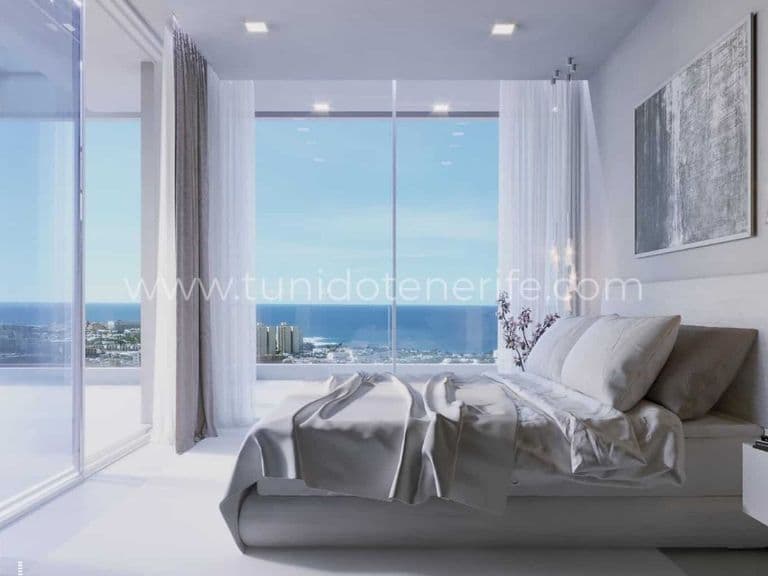 Bright bedroom with bed and large windows facing the sea