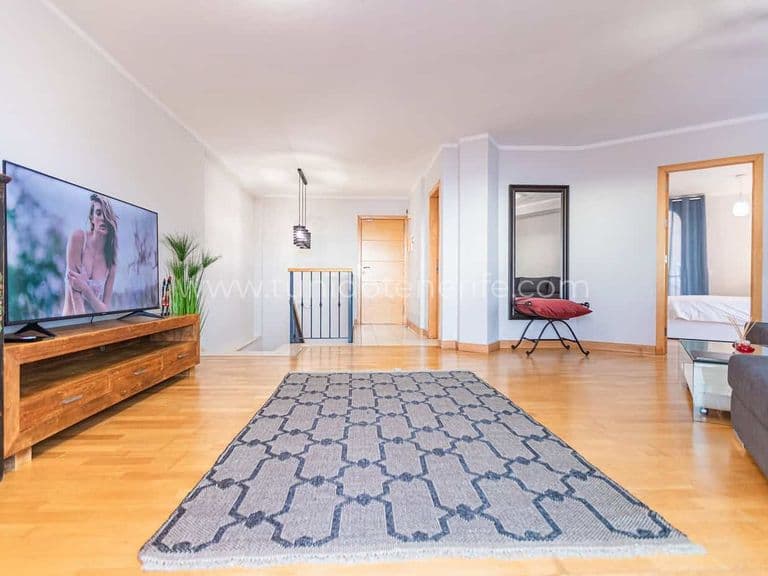 Salón amplio y luminoso con sofá, televisión y alfombra