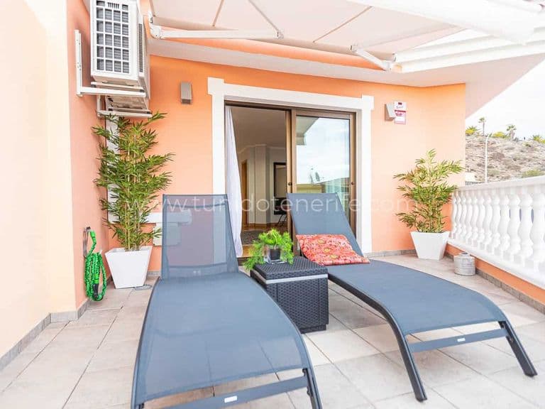 Terraza con tumbonas, mesa auxiliar y plantas en macetas