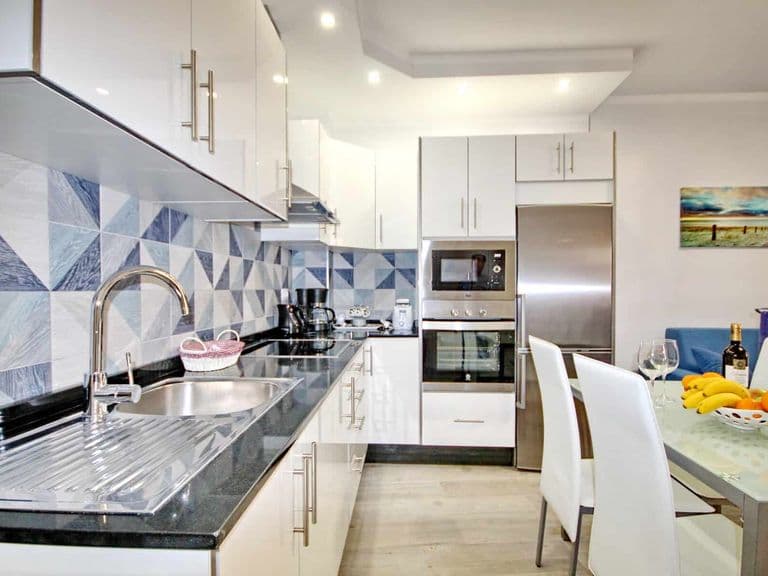 Cucina moderna bianca con piano nero e zona pranzo