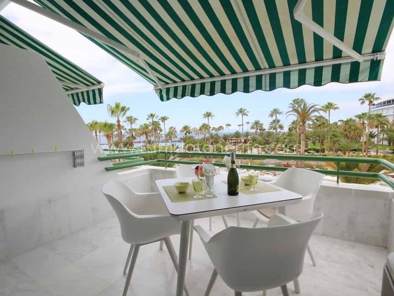 Terrace with table, chairs and green striped awning