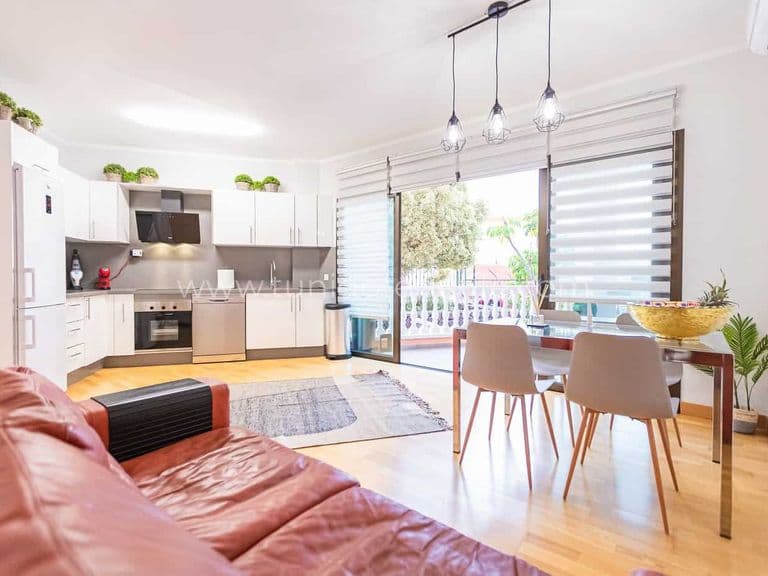 Salón con cocina abierta, mesa de comedor y salida a terraza