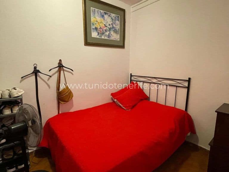 Bedroom with red single bed and wall painting