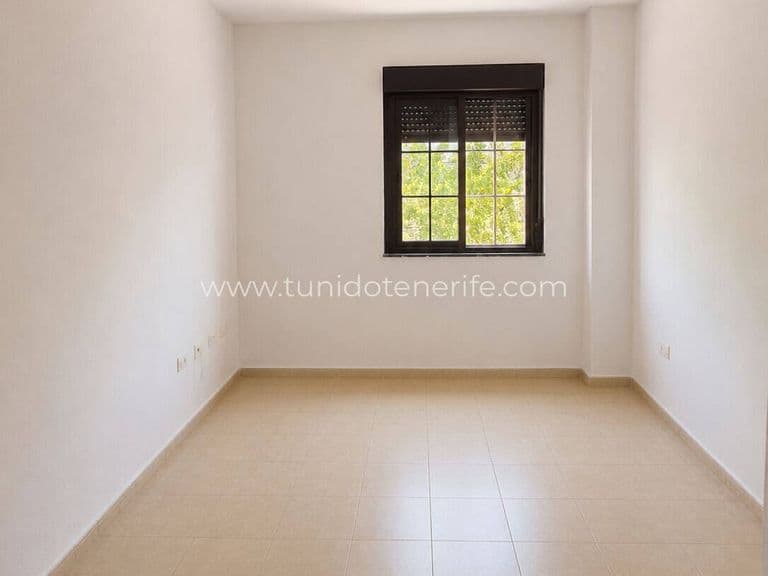 Habitación vacía con ventana y suelo de baldosas