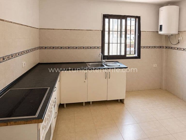 Cocina vacía con encimera negra, fregadero y ventana