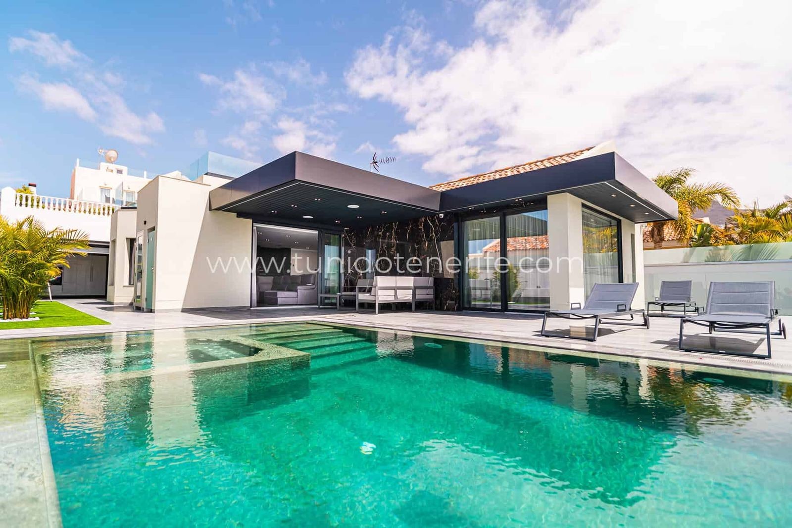 Piscina exterior junto a la terraza y fachada acristalada