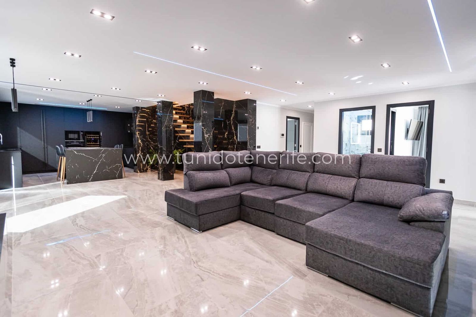 Salón moderno con sofá gris en esquina y suelos de mármol