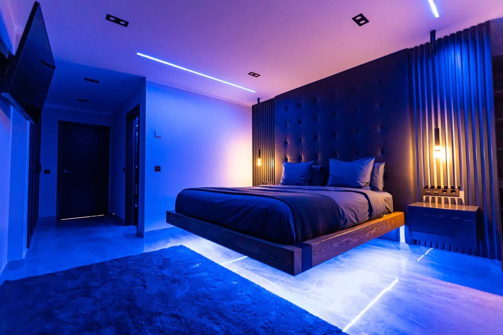 Dormitorio moderno con iluminación azul y cabecero capitoné