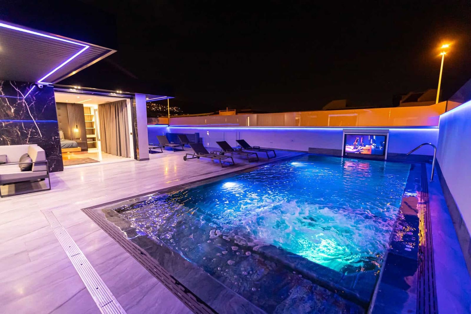 Piscina iluminada junto a terraza nocturna