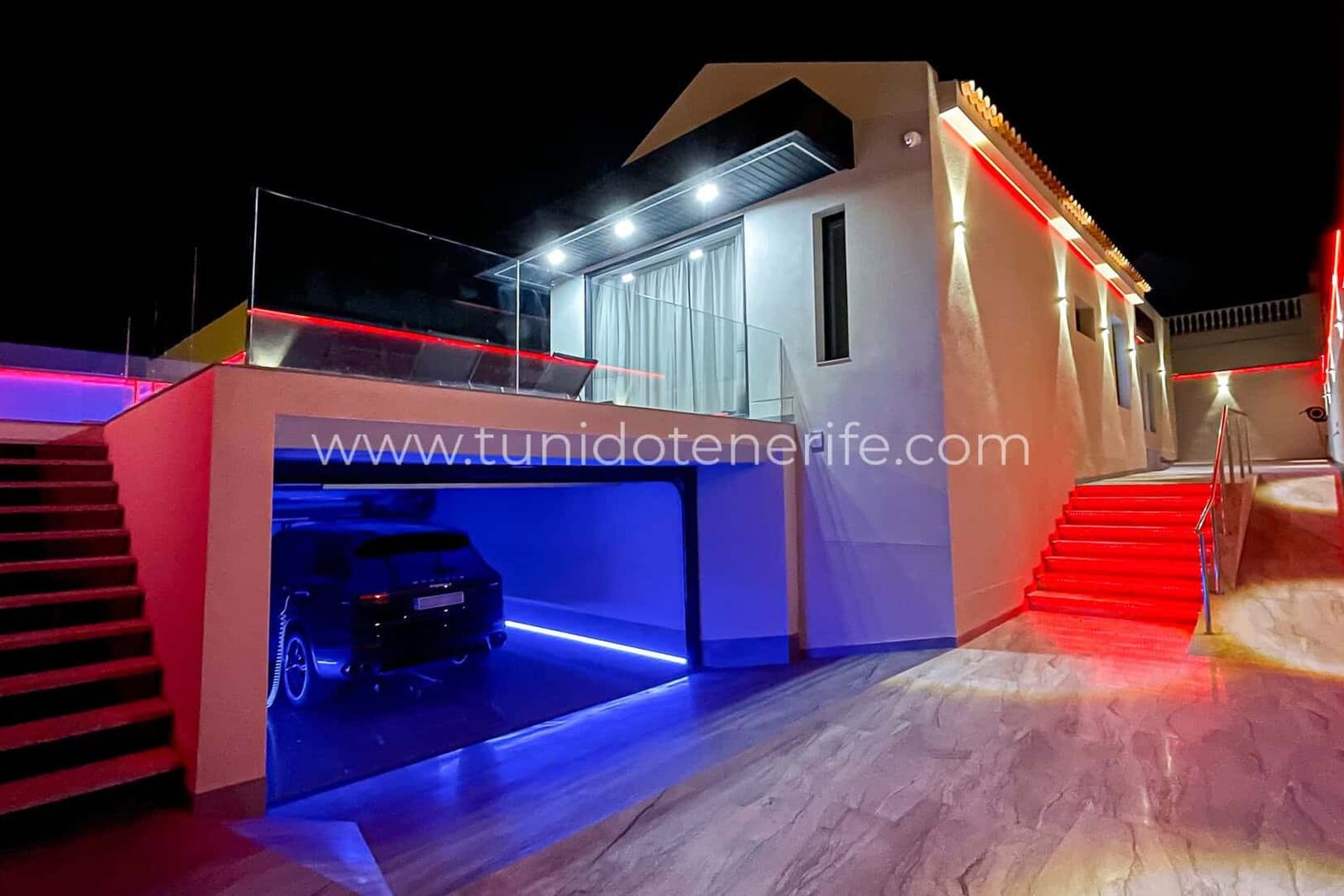 Garaje iluminado con coche estacionado y escaleras rojas