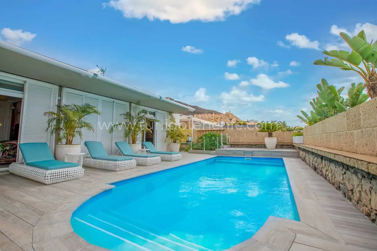 Piscina exterior con tumbonas y cielo despejado