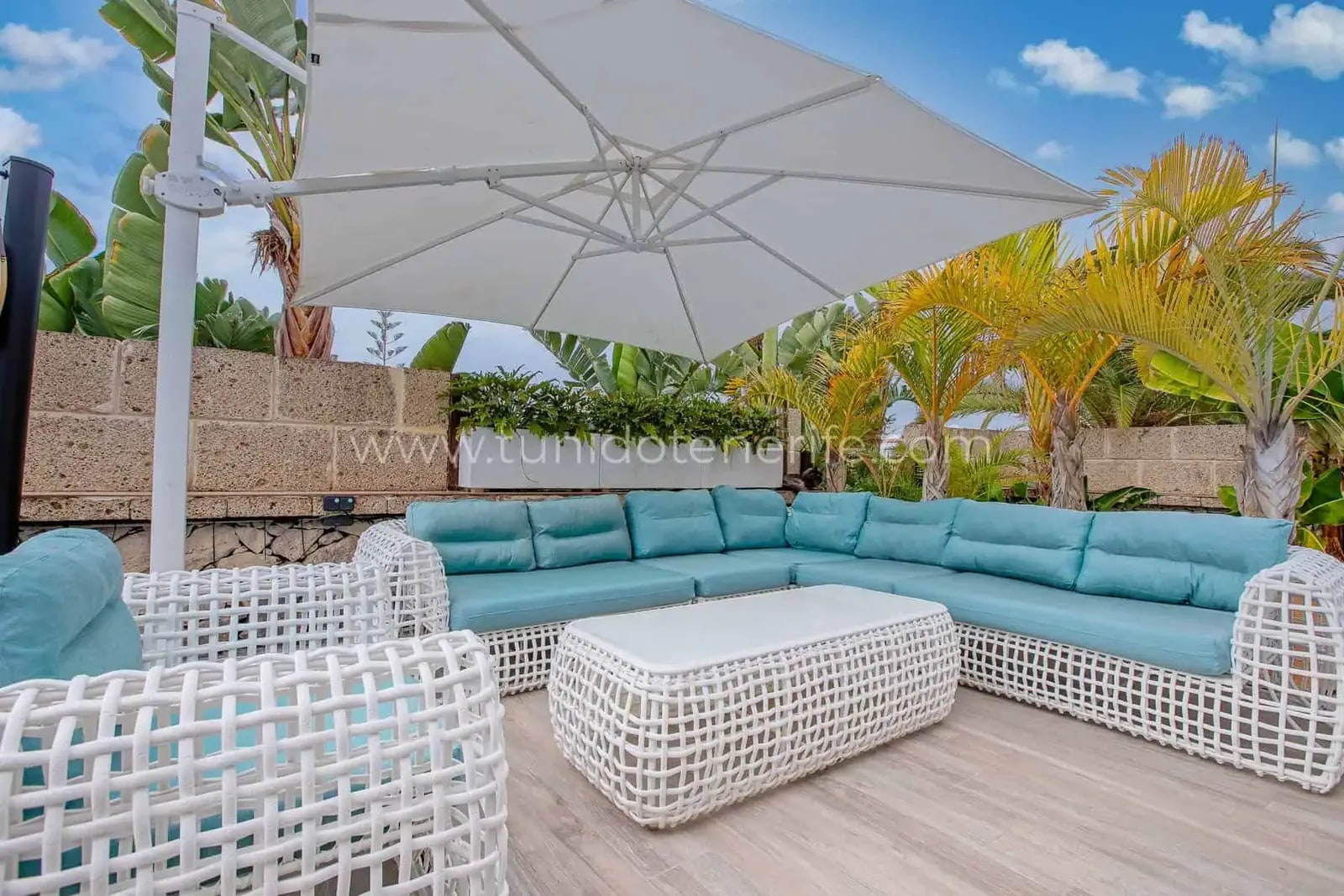 Terraza con sofá en L, mesa baja y gran parasol