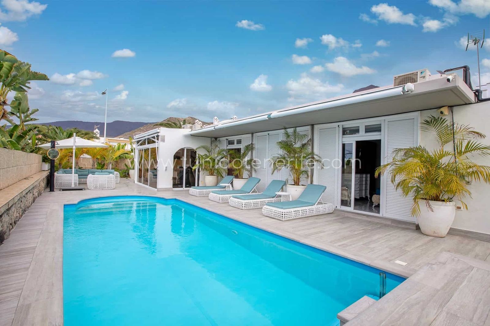Piscina exterior con tumbonas y cielo despejado