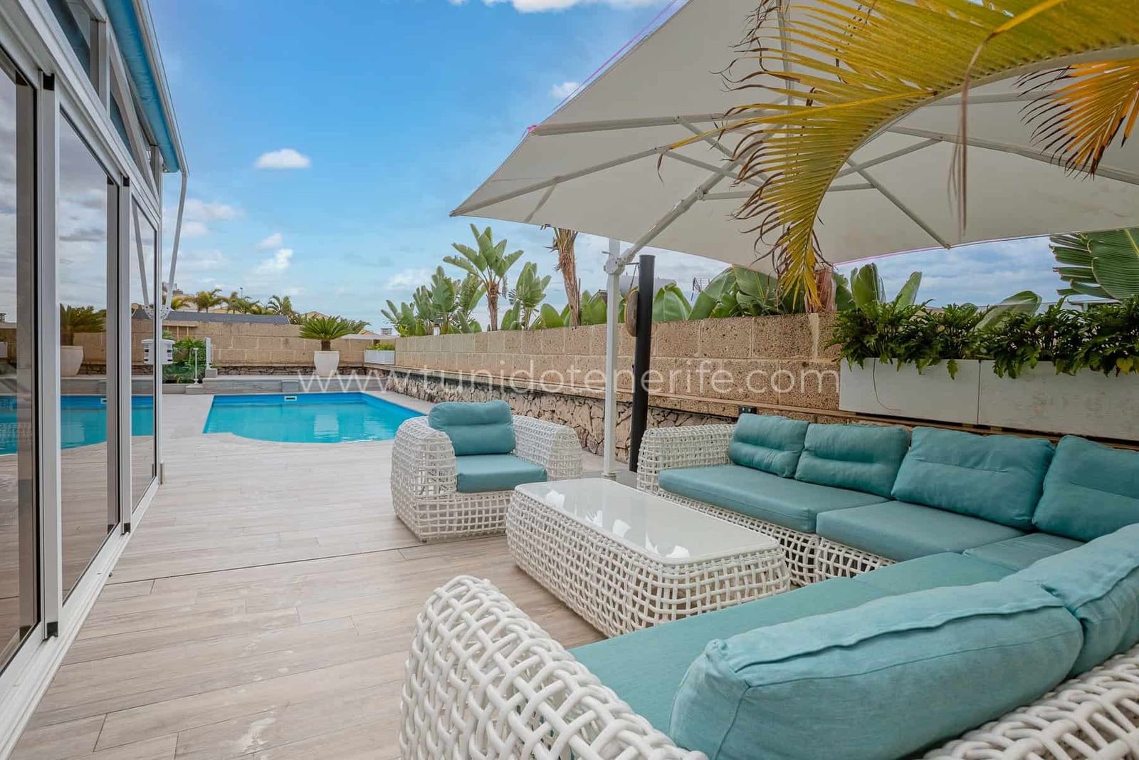 Terraza con sofá exterior, mesa y piscina