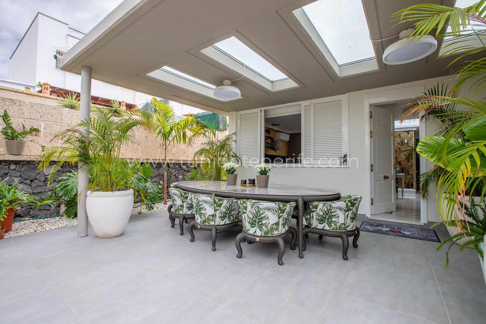 Terraza cubierta con mesa, sillones y plantas