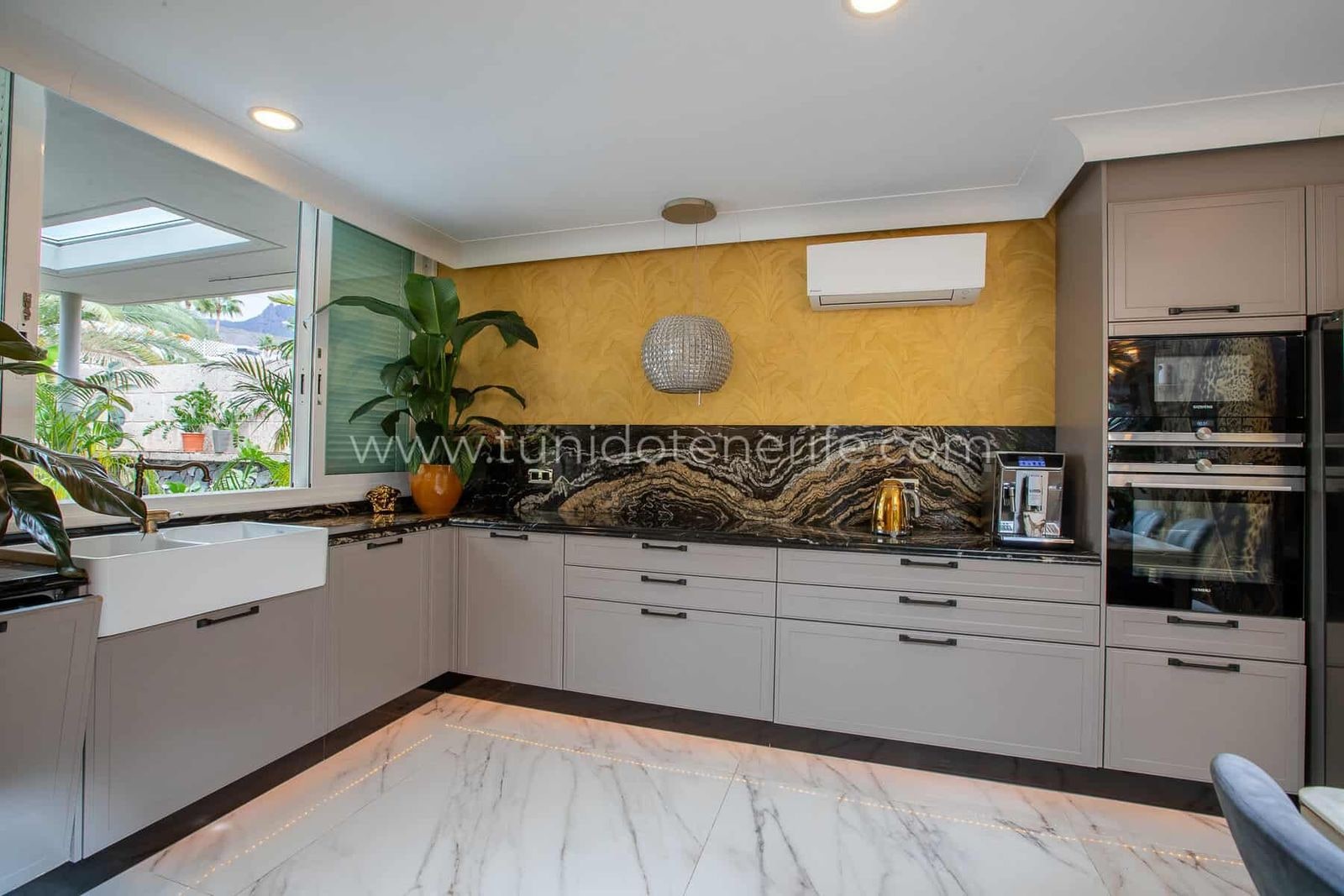 Cocina moderna con encimera oscura, planta y ventana al exterior