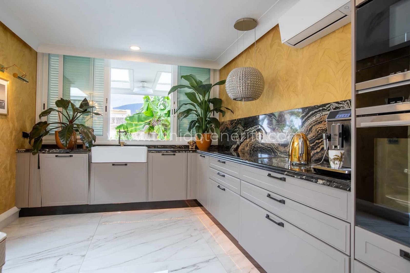 Cocina moderna con armarios blancos, encimera negra y plantas