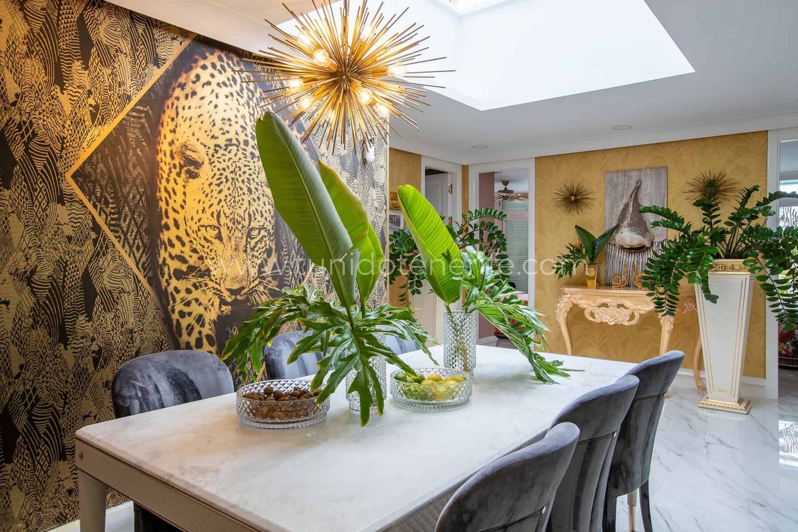 Comedor elegante con mesa blanca, sillas grises y decoración tropical