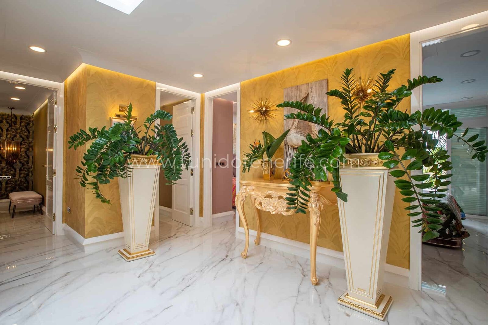 Recibidor elegante con consola decorativa y plantas altas