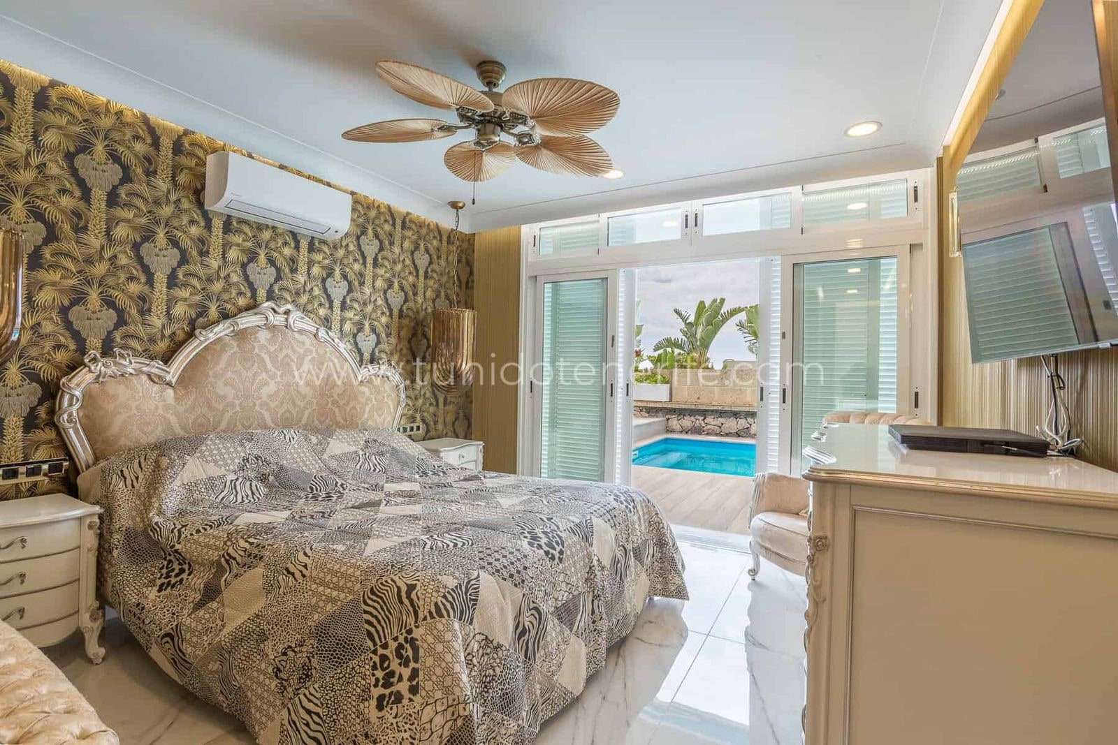 Dormitorio con cama estampada y salida a la piscina
