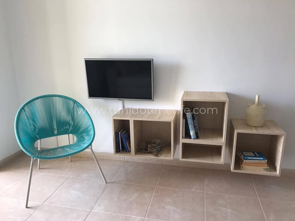 Living cu rafturi modulare, televizor și scaun turcoaz