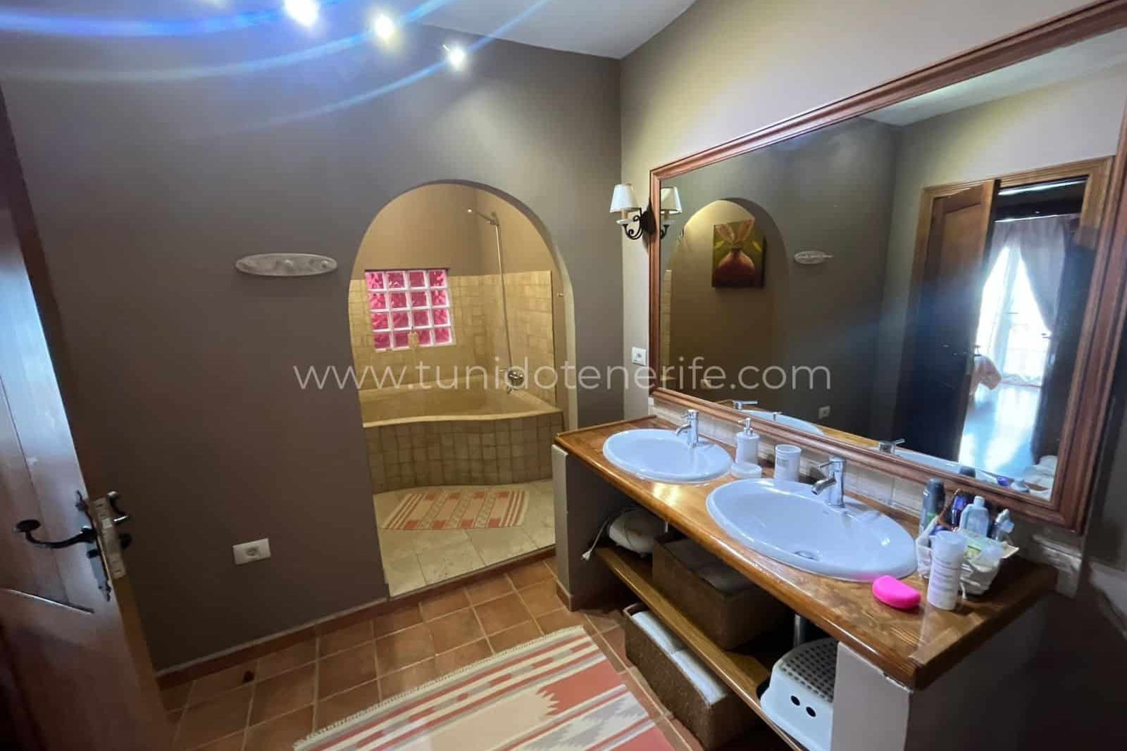 Bathroom with double sink, large mirror and semicircular shower