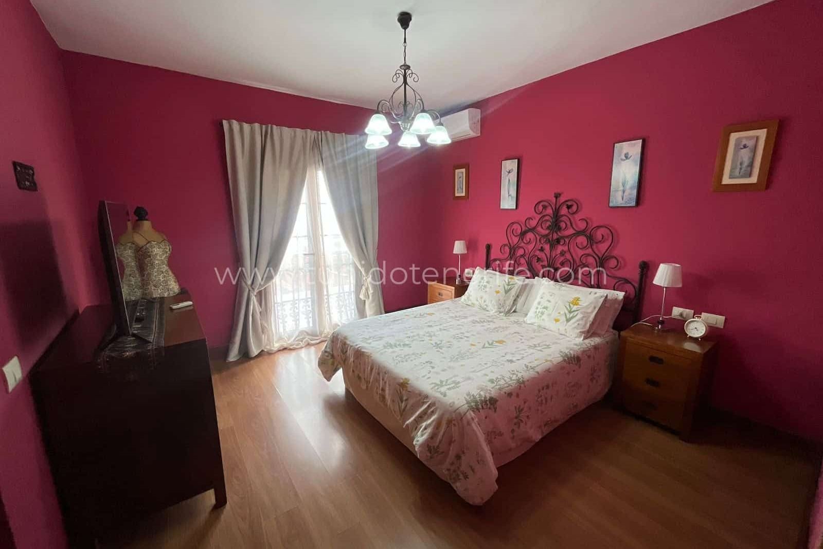 Bedroom with double bed, fuchsia walls and natural light