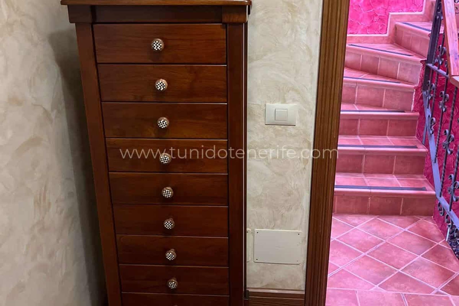 Wooden dresser next to a pink tiled staircase