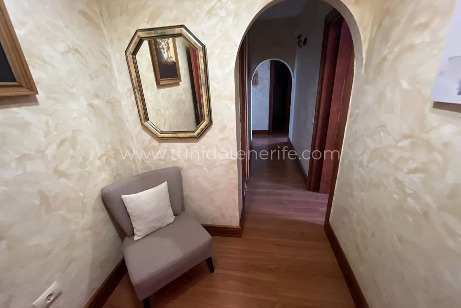Narrow hallway with upholstered chair and decorative mirrors