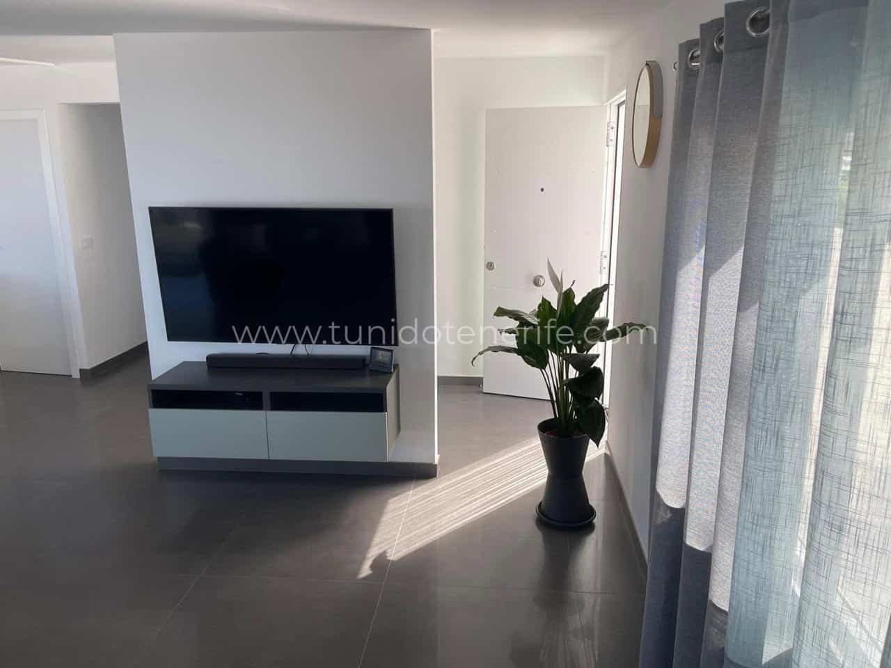 Living luminos cu televizor, perdele gri și plantă decorativă