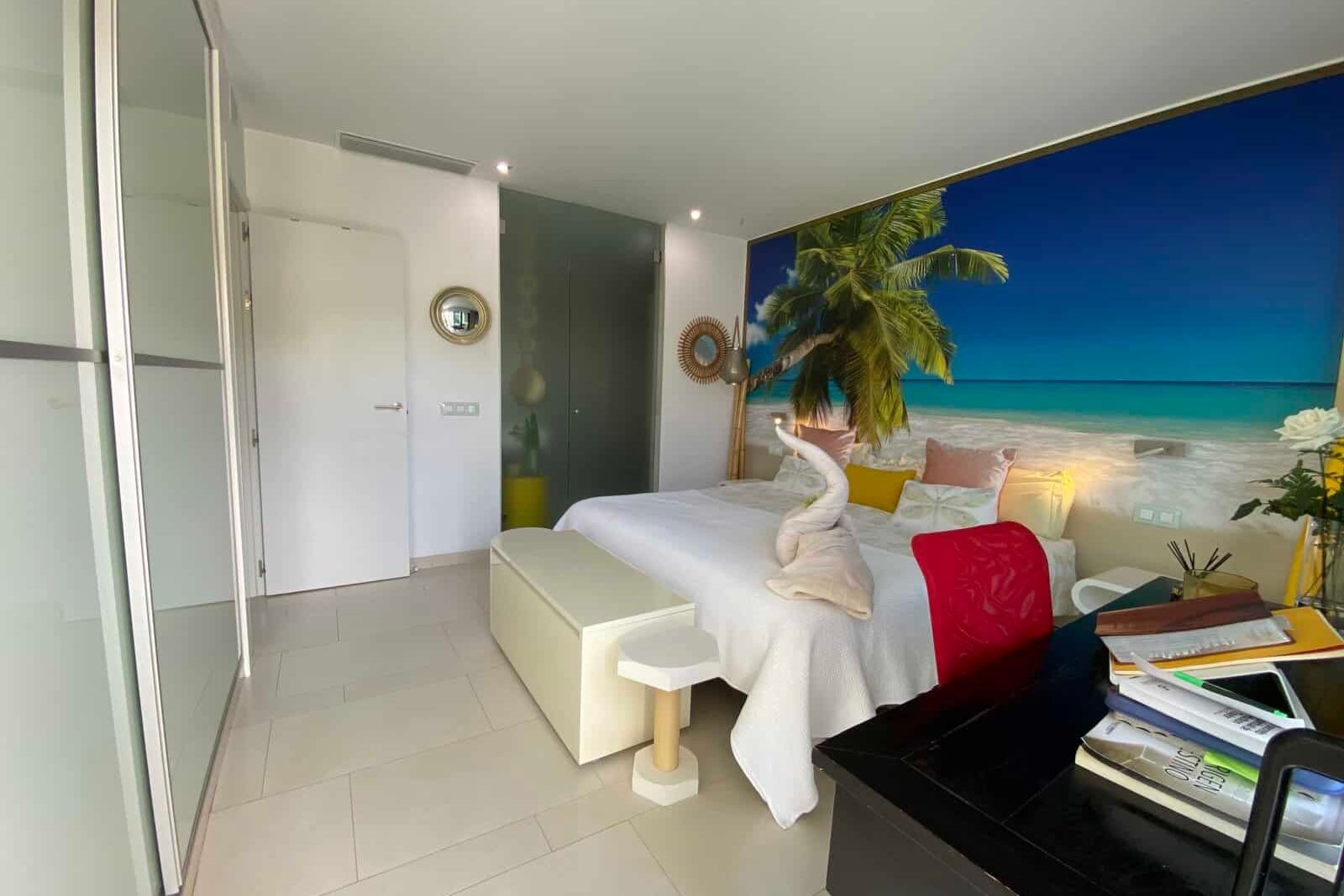 Bright bedroom with white bed, wardrobe and tropical mural