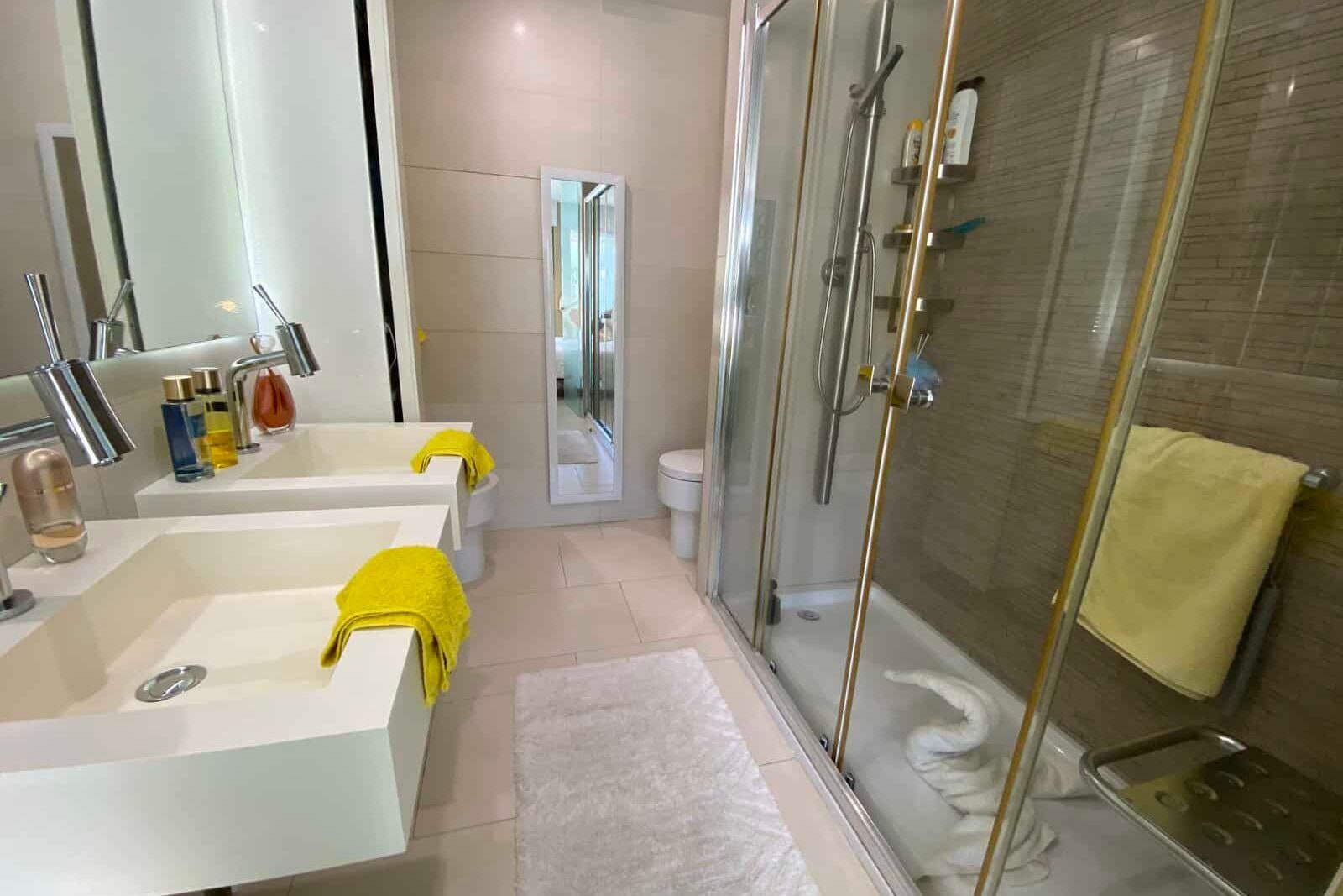 Modern bathroom with glass shower double sink and mirror