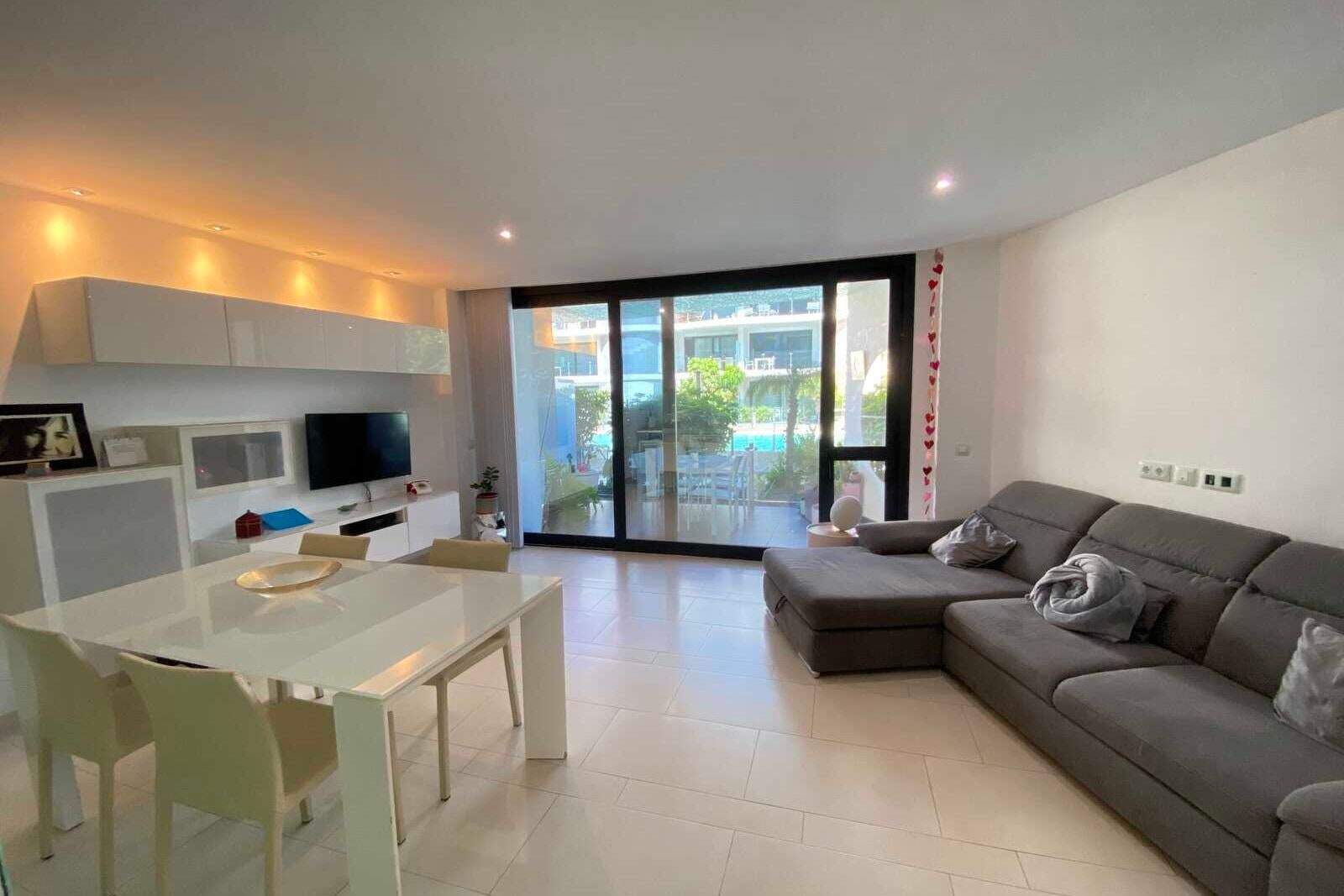 Living-dining room with gray sofa, glass table and large windows
