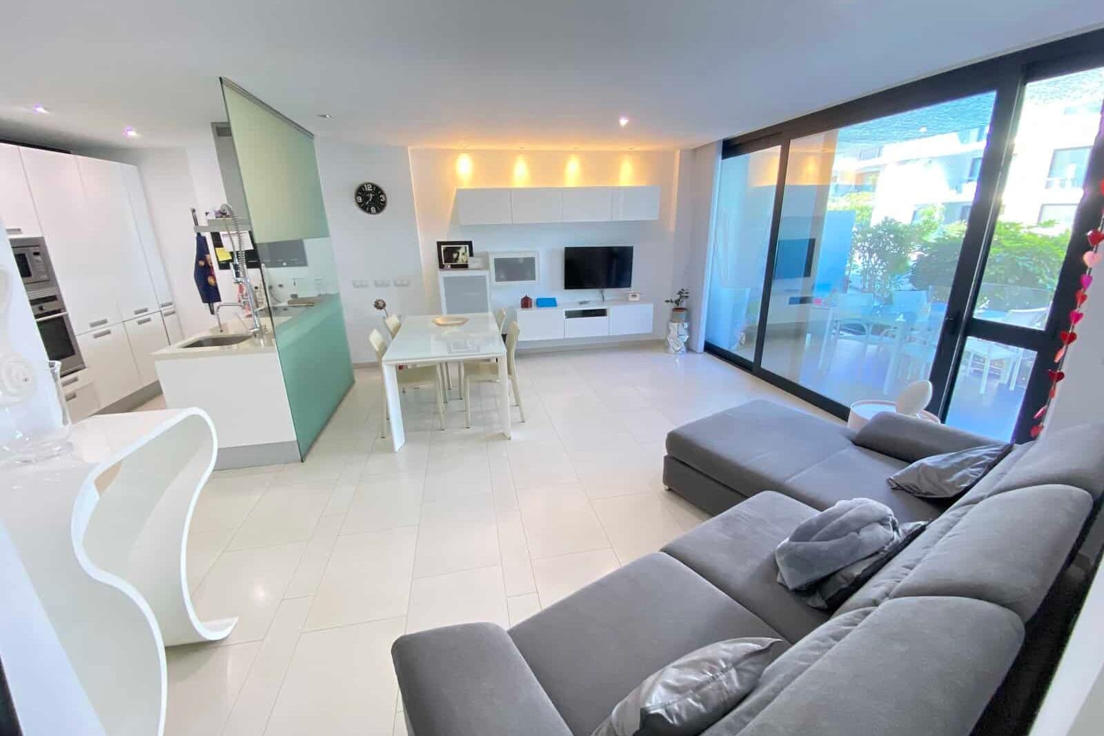 Bright living room with gray sofa, dining table and large windows