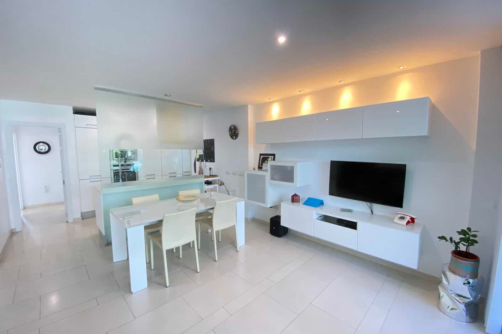 Open-plan living dining room with white furniture and television