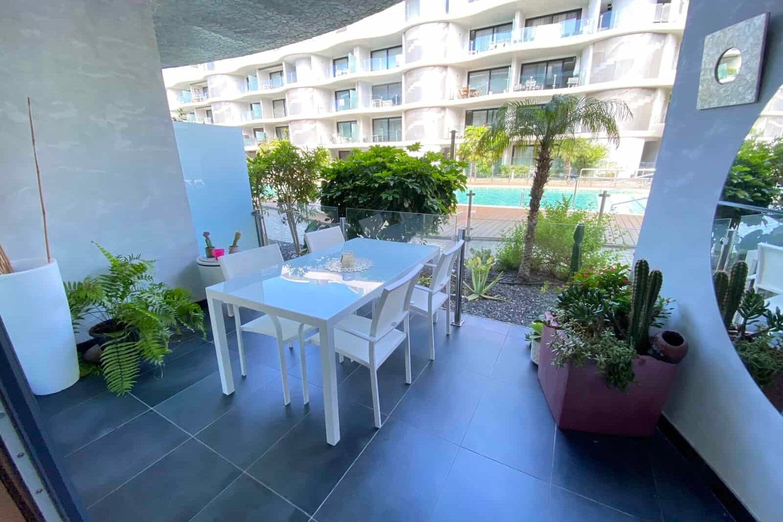Terrace with table, chairs, plants and pool view