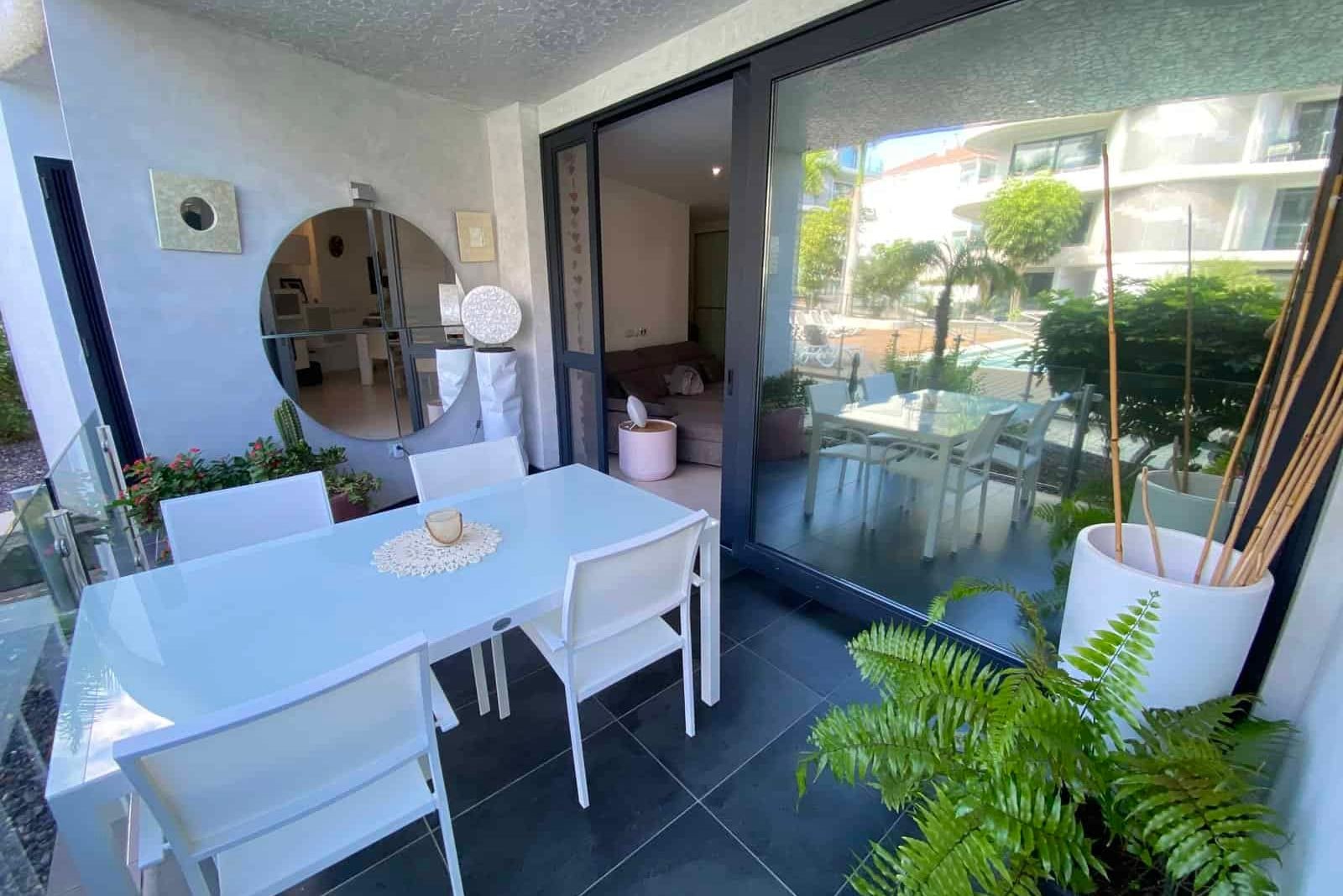 Covered terrace with white table, chairs and plants