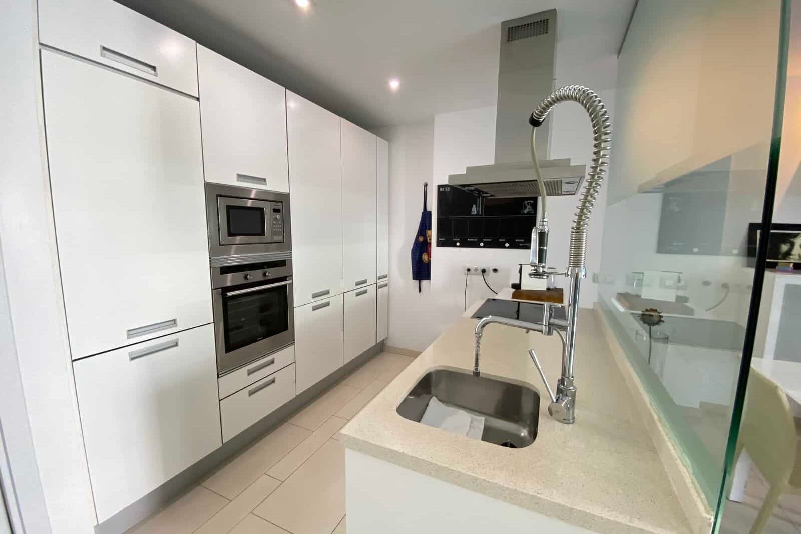 Modern white kitchen with island and tall faucet