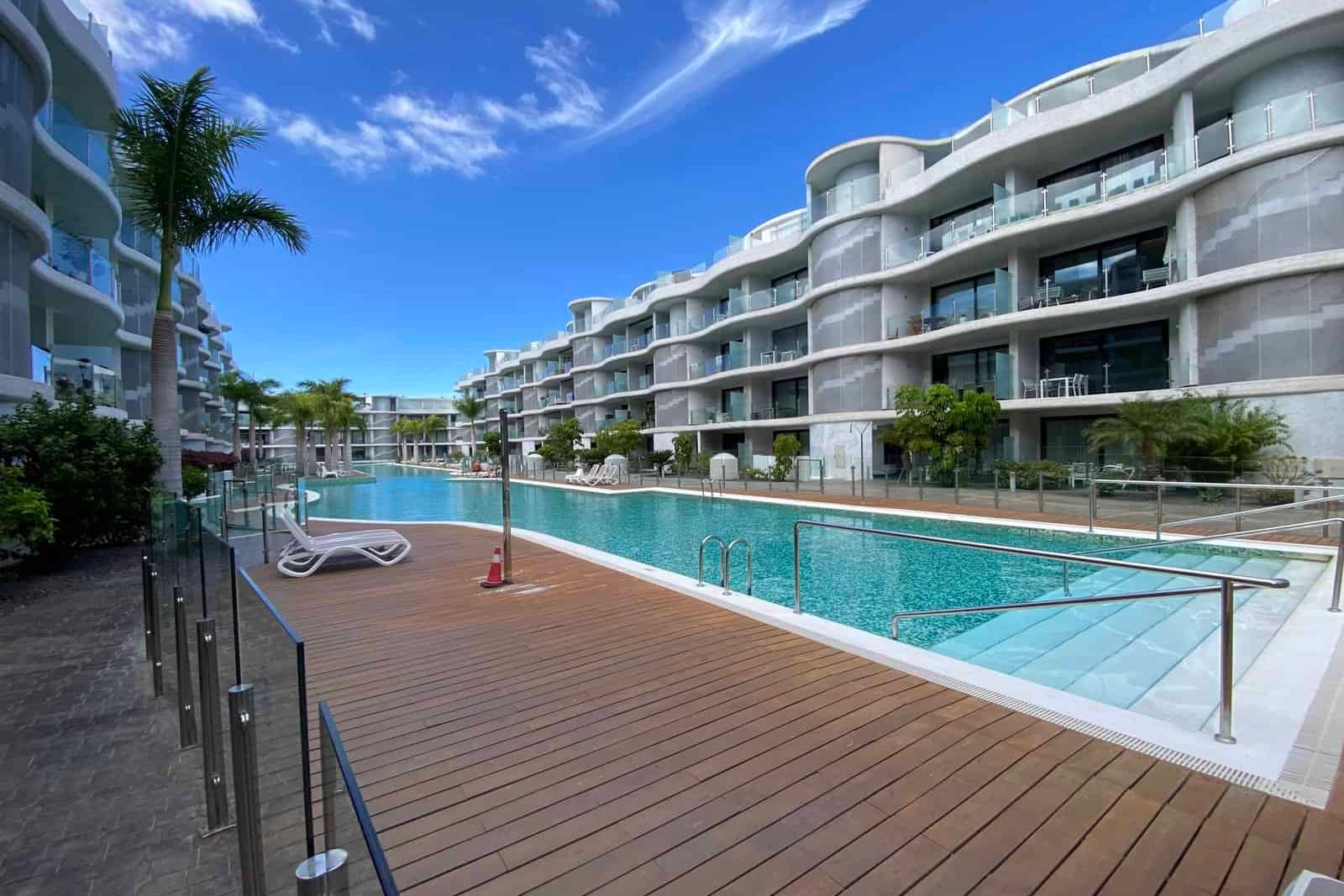 Outdoor pool with wooden terrace and modern buildings