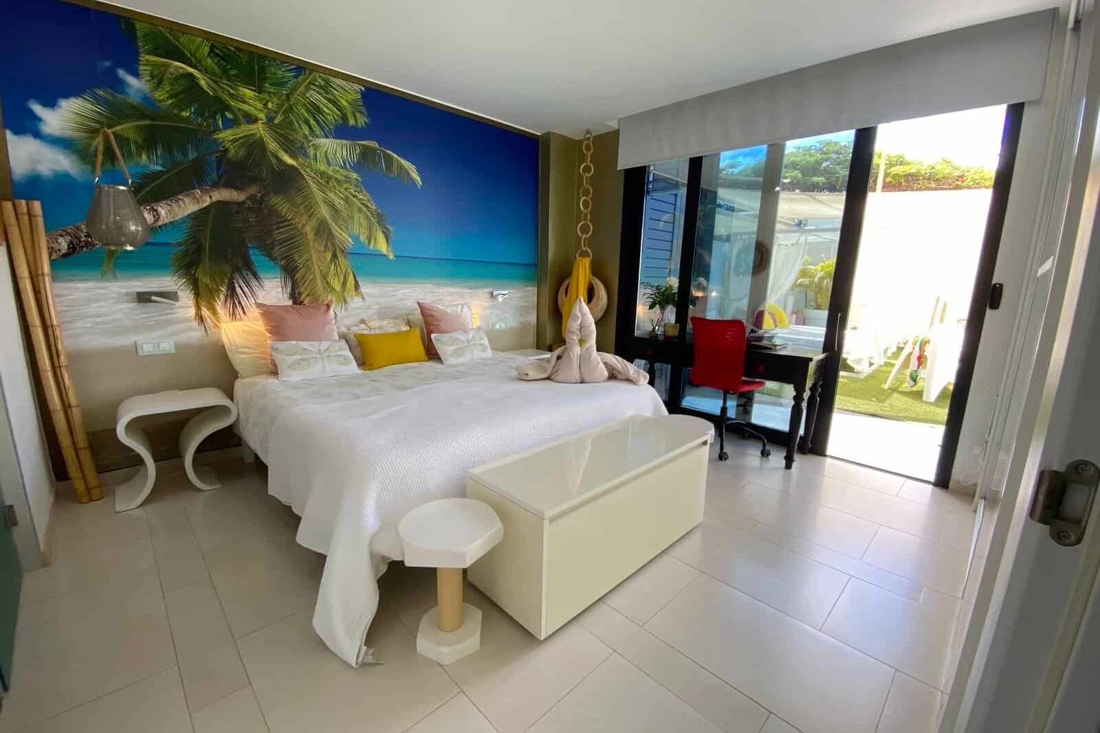 Bedroom with tropical mural, white bed and outdoor terrace